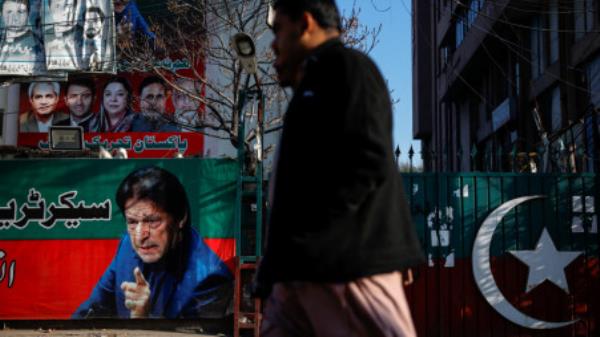 People walk past a banner with a picture of the former Prime Minister Imran Khan outside the party office of Pakistan Tehreek-e-Insaf (PTI), a day after the general election, in Lahore, Pakistan, February 9, 2024. REUTERS/Navesh Chitrakar