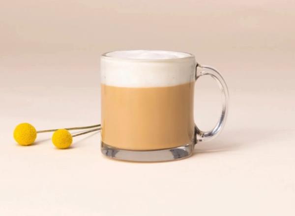 a mug of starbucks blo<em></em>nde vanilla latte on a plain background with a yellow garnish.